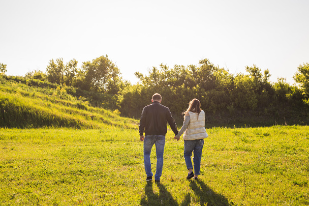 Пара прогулок на осеннем лугу захода солнца, держась за руки
 - Фото, изображение