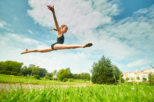 Young beautiful preteen girl doing gymnastics outdoors - Фото, изображение