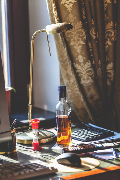 Bottle of alcohol and hourglass on your desktop - 写真・画像