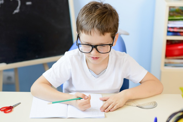 7 ans garçon résout table de multiplication dans son copybook. Retour à l'école
 - Photo, image
