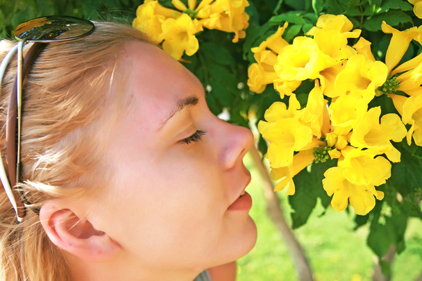 mujer joven oliendo una flor amarilla
 - Foto, imagen