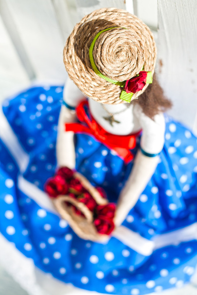 boneca tilde em uma saia azul e um chapéu de palha com uma cesta com fl
 - Foto, Imagem