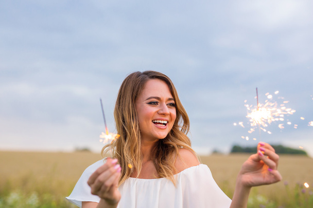 Portrait of young attractive celebrating woman holding sparkles. - Valokuva, kuva