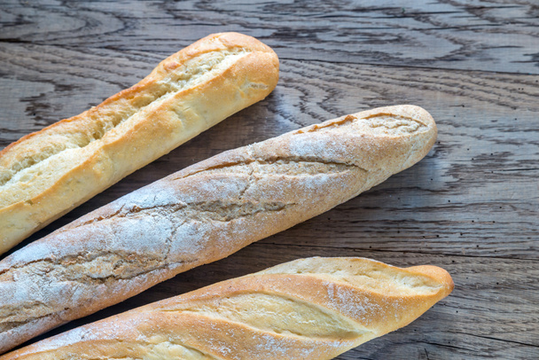 Three baguettes on the wooden background - Foto, afbeelding