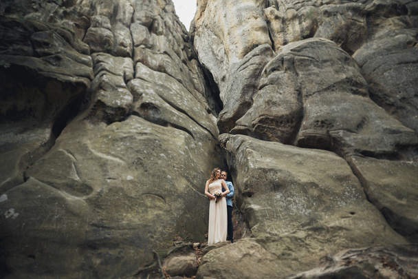 Happy wedding couple kissing and hugging near a high cliff - 写真・画像