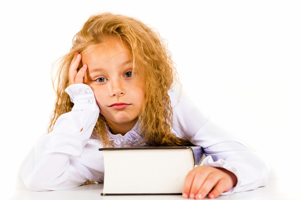 Portrait of a tired little girl with a book on a white background - Foto, afbeelding
