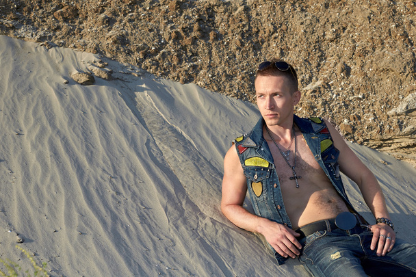 Portrait of a man in denim clothes on the sand. - 写真・画像