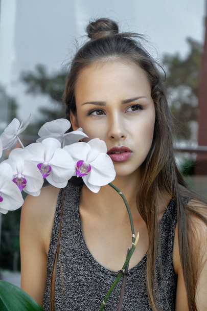 Girl with orchid flower is very sad. - Фото, зображення