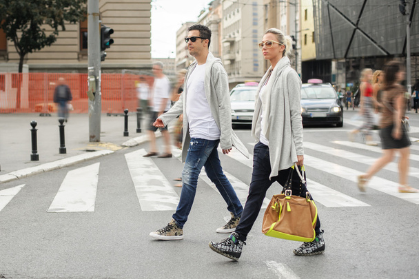 Fashionable couple crossing road at pedestrian zebra crossing - Photo, Image