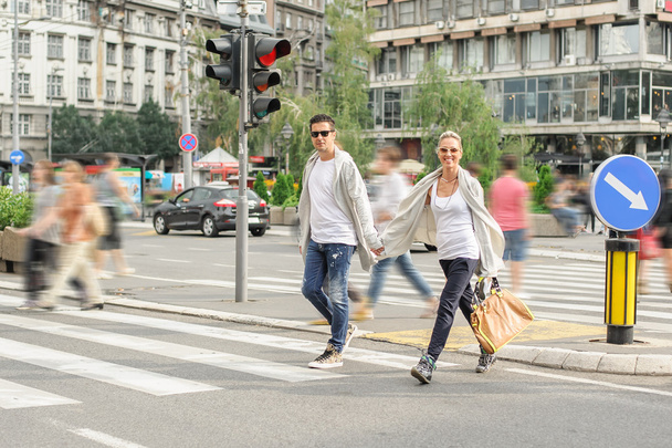 Fashionable couple crossing road at pedestrian zebra crossing - Фото, изображение