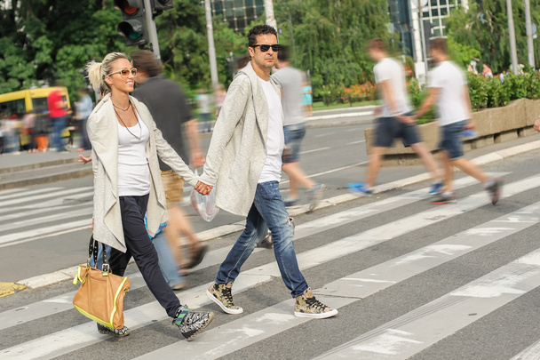 Fashionable couple crossing road at pedestrian zebra crossing - Фото, зображення