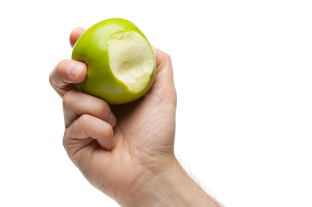 Mano sosteniendo manzana verde con mordida faltante
 - Foto, Imagen