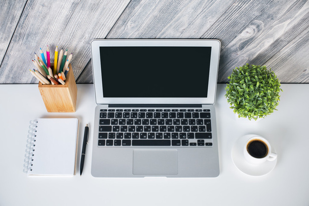 Creative designer desktop with blank laptop, notepad, pen, pencils, coffee cup and plant on wooden background. Mock up - Fotoğraf, Görsel