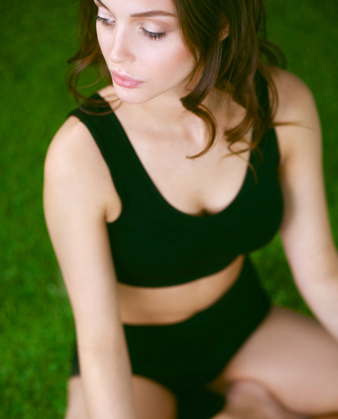 Woman sitting with crossed legs on the green grass - Foto, Imagem