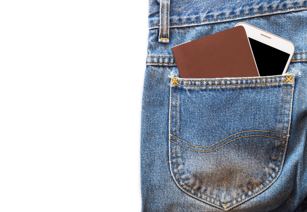 Witte smartphone en paspoort of lege notitie boek in uw zak blue jeans op geïsoleerde achtergrond. kopie ruimte - Foto, afbeelding