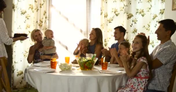 Szczęśliwy multi generacji rodziny obchodzi urodziny babci i klaskanie ręce, a ona zdmuchujące świeczki na tort - Materiał filmowy, wideo