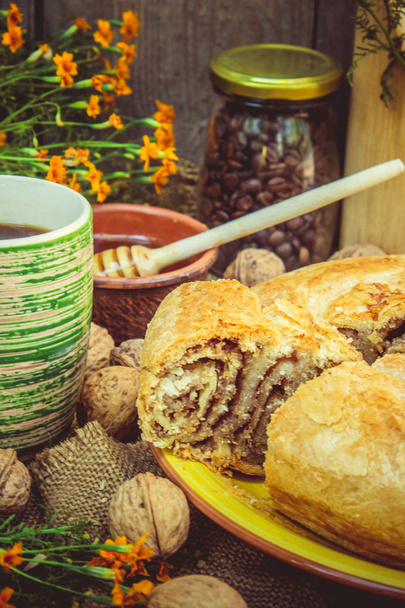 Pastel casero de hojaldre horneado con nueces y una taza de café caliente para el desayuno
. - Foto, imagen