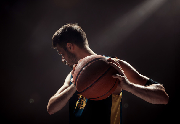Silhouette view of a basketball player holding basket ball on black background - Foto, Imagem
