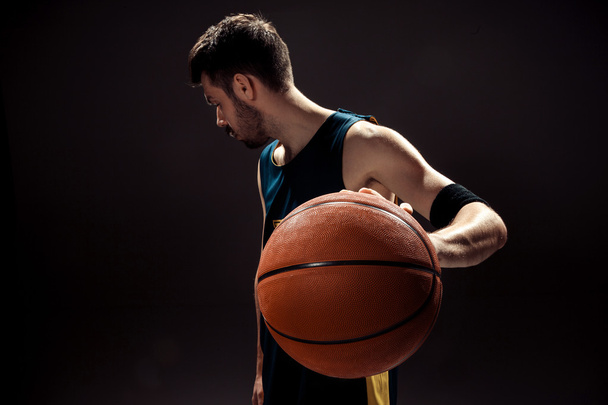 Vista silhueta de um jogador de basquete segurando bola cesta no fundo preto
 - Foto, Imagem