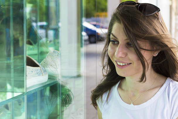 Счастливая девушка смотрит в витрину магазина
 - Фото, изображение