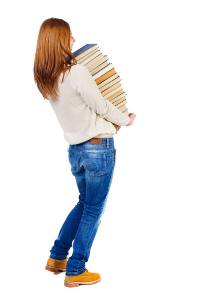 Dziewczyna nosi ciężki stos książek. Widok z tyłu. - Zdjęcie, obraz