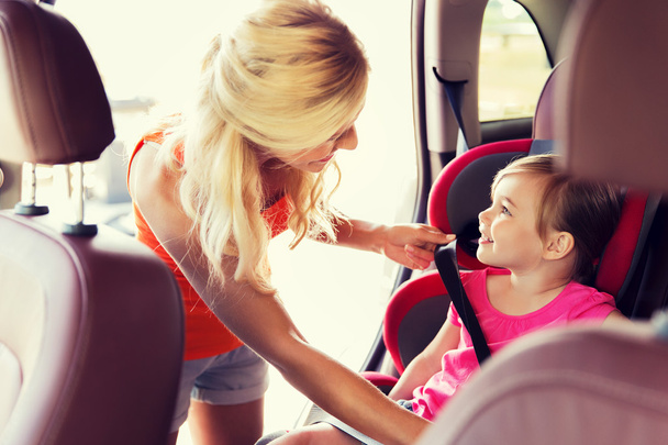 happy mother fastening child with car seat belt - Foto, afbeelding