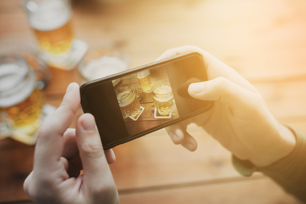 close up of hands with smartphone picturing beer - Foto, imagen