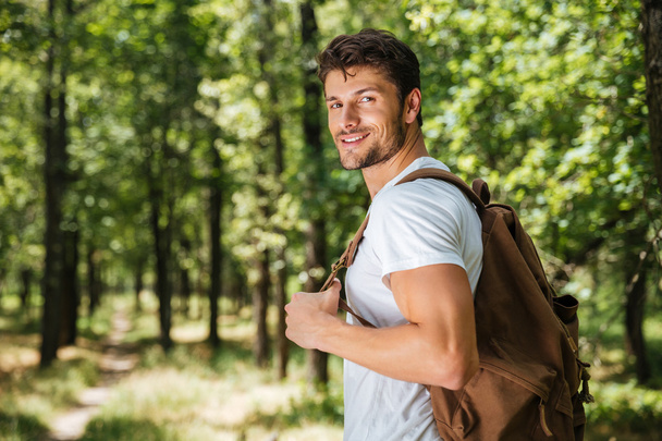 Man with backpack walking in forest - Fotoğraf, Görsel