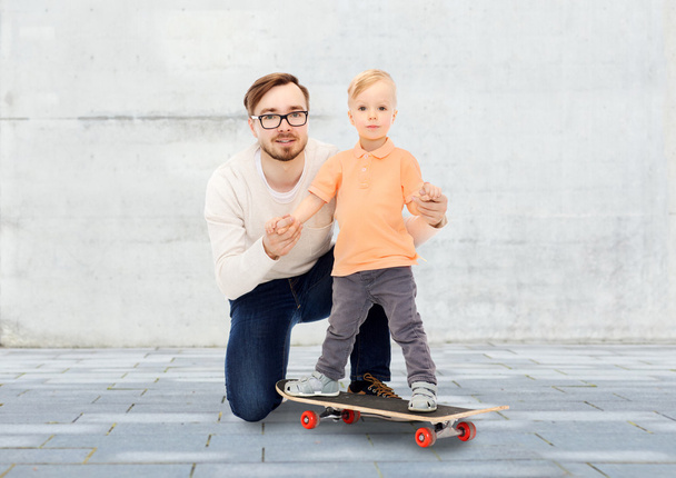 happy father and little son on skateboard - 写真・画像
