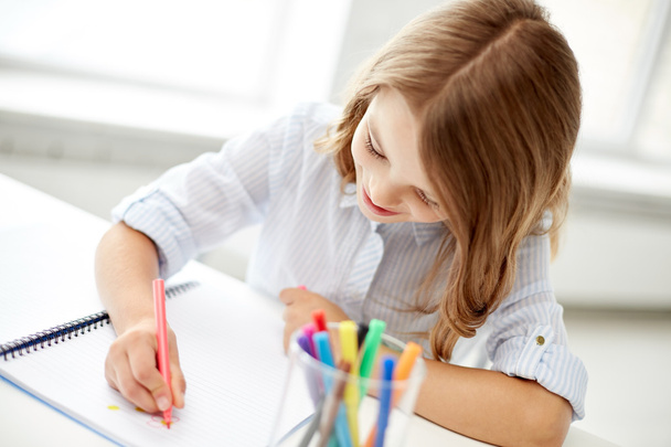 happy girl drawing with felt-tip pen in notebook - Foto, Imagem