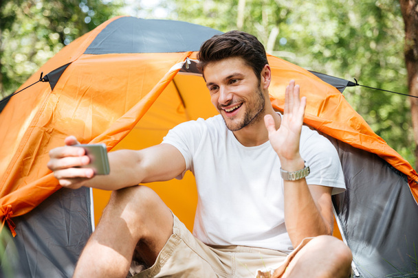 Smiling man tourist taking selfie with smartphone at touristic tent - Fotó, kép
