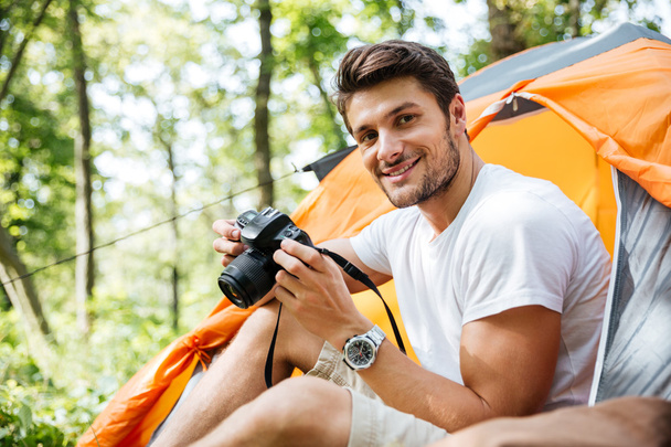 Man tourist sitting and using photo camera in touristic tent - Photo, Image