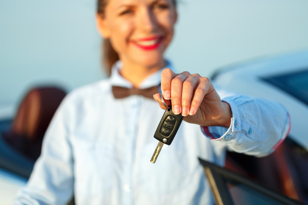 junge Frau steht neben einem Cabrio mit Schlüssel in der Hand - Foto, Bild