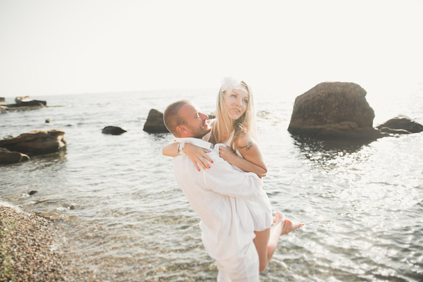 happy just married young wedding couple celebrating and have fun at beautiful beach sunset - Photo, image