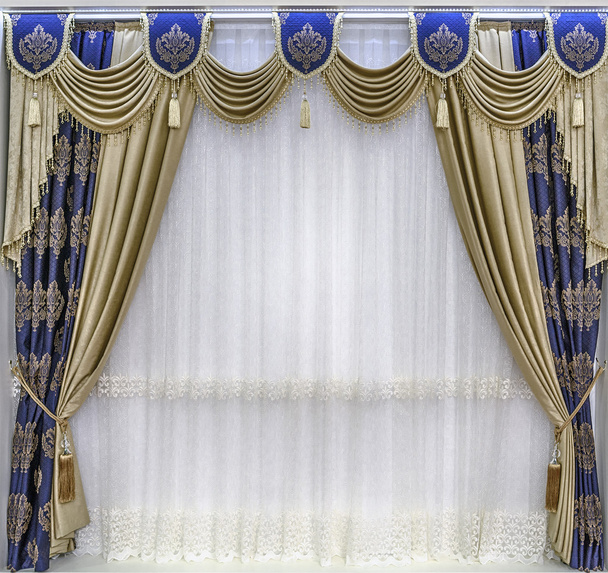 Le design luxueux des fenêtres et des murs. Draperies, pelmet et tulle. La combinaison de rideaux dorés et le tissu bleu avec des ornements
. - Photo, image