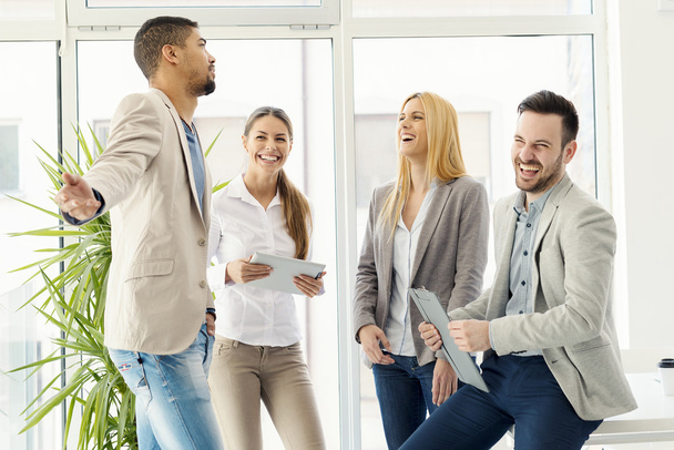 Ryhmä hymyileviä liikemiehiä seisomassa ja kommunikoimassa
 - Valokuva, kuva
