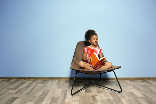 Cute girl reading book on blue wall background - Foto, Imagen
