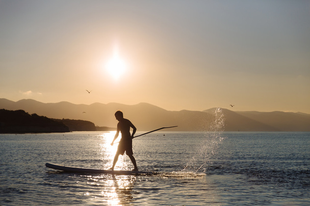 silhouette of young boy paddle boarding at sunset. concept  lifestyle sport - Foto, Bild