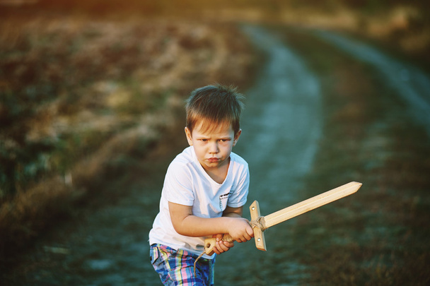 egy kisfiú játszik egy fából készült kard - Fotó, kép
