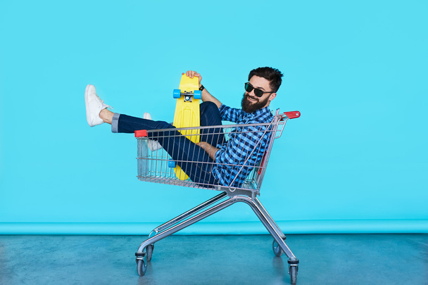 Young man sitting in shopping cart - Foto, imagen