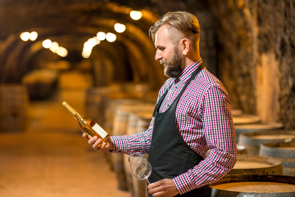 Sommelier with wine bottle in cellar - Photo, Image