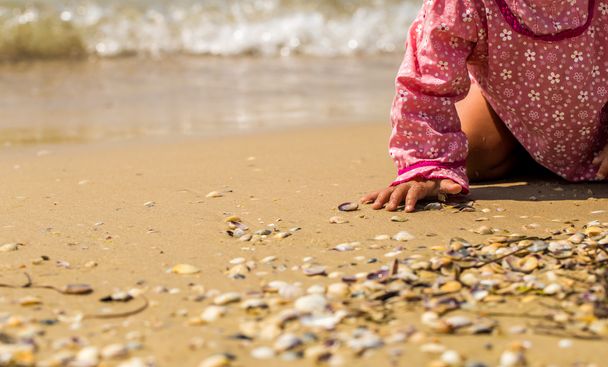 hübsches kleines Mädchen, das am Strand kriecht, das fröhliche Kind, Emotionen - Foto, Bild