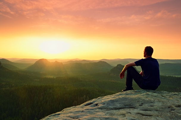 孤独の瞬間男は岩のピークに座って、夜明けを楽しむ - 写真・画像