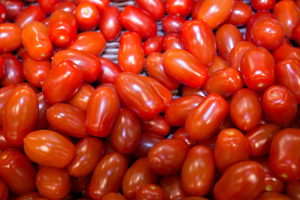 Κόκκινες ντομάτες στην υπαίθρια αγορά, κόκκινο φόντο - Φωτογραφία, εικόνα
