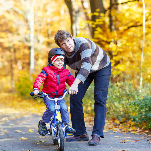 Mały chłopiec dziecko i ojca z rowerem w lesie jesienią - Zdjęcie, obraz