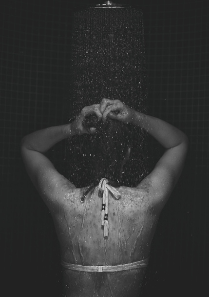 Mujer joven disfrutando en la ducha. Vista trasera. Foto en blanco y negro
. - Foto, Imagen