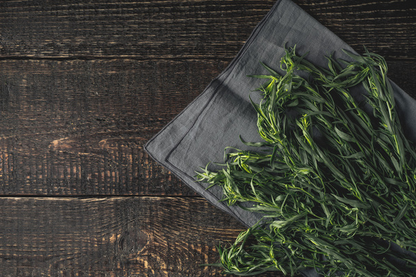 Tarragon on the grey napkin on the wooden table top view - Фото, изображение