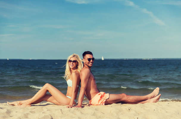 happy couple in swimwear sitting on summer beach - Valokuva, kuva