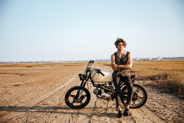 Young brutal man leaning on a motorcycle - Foto, immagini