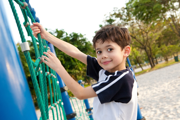 Young boy enjoying the playground climbing activity. - Фото, зображення
